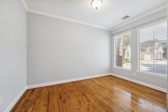 spare room with a textured ceiling, hardwood / wood-style floors, and crown molding