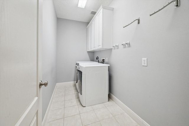 laundry area with a textured ceiling, cabinets, independent washer and dryer, and light tile patterned floors