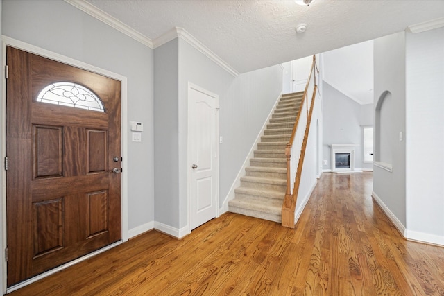 foyer featuring ornamental molding, a wealth of natural light, a textured ceiling, and wood-type flooring