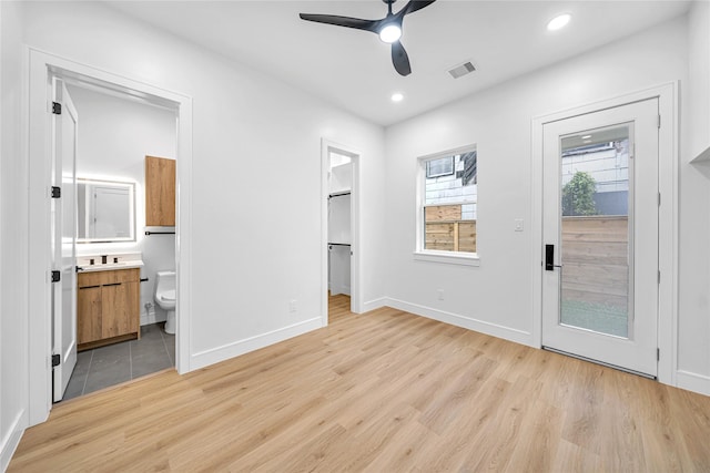 unfurnished bedroom with ensuite bath, ceiling fan, and light wood-type flooring