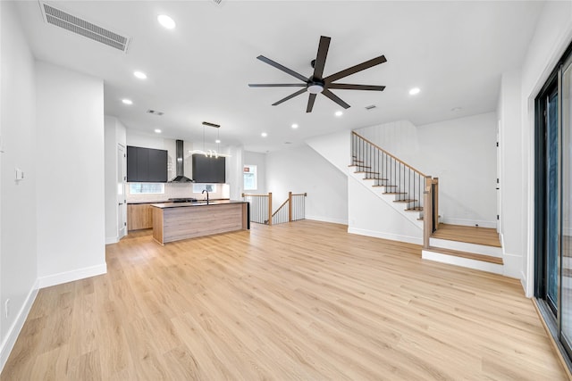 unfurnished living room featuring light wood-type flooring, ceiling fan, and sink