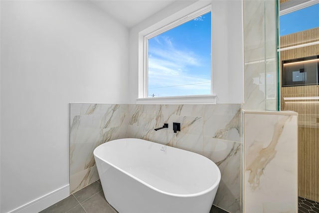 bathroom featuring tile walls, tile patterned floors, and a bath