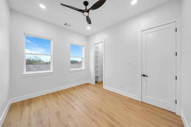 unfurnished bedroom featuring ceiling fan, light hardwood / wood-style flooring, and a spacious closet