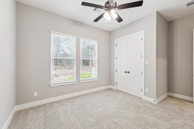 unfurnished bedroom featuring ceiling fan, light colored carpet, and a closet