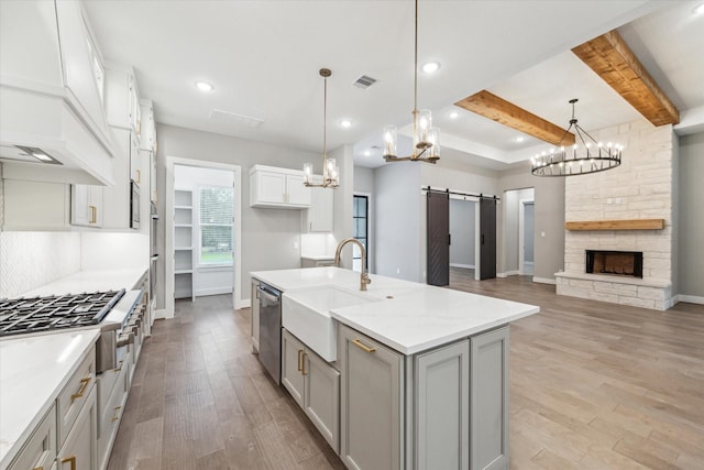 kitchen featuring appliances with stainless steel finishes, a barn door, hanging light fixtures, and beamed ceiling