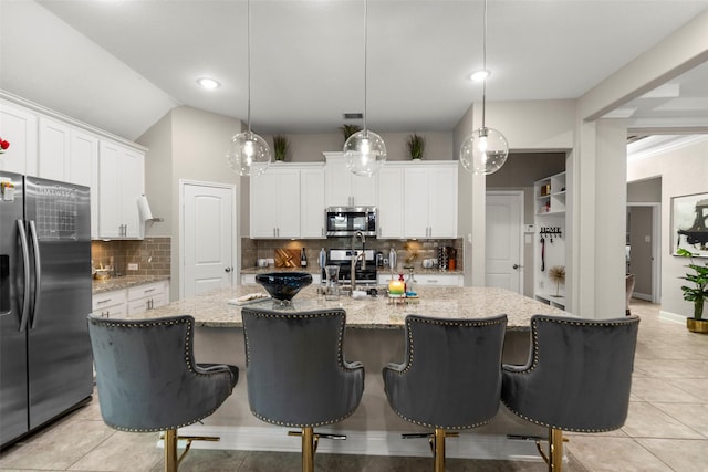 kitchen featuring stainless steel appliances, white cabinetry, a kitchen island with sink, and decorative light fixtures