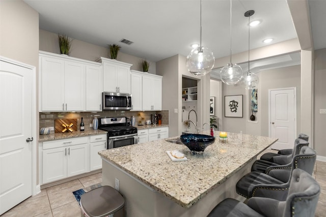 kitchen featuring pendant lighting, white cabinetry, stainless steel appliances, and an island with sink