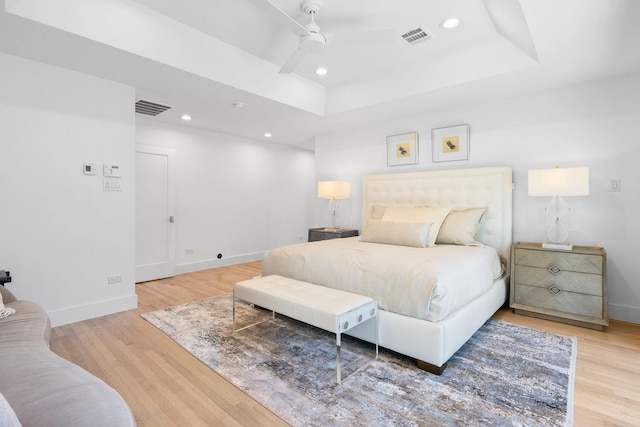 bedroom with a raised ceiling, ceiling fan, and hardwood / wood-style flooring