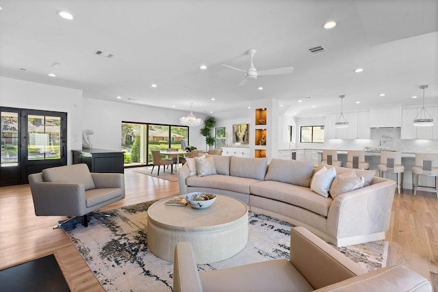 living room featuring a healthy amount of sunlight, light wood-type flooring, and ceiling fan with notable chandelier