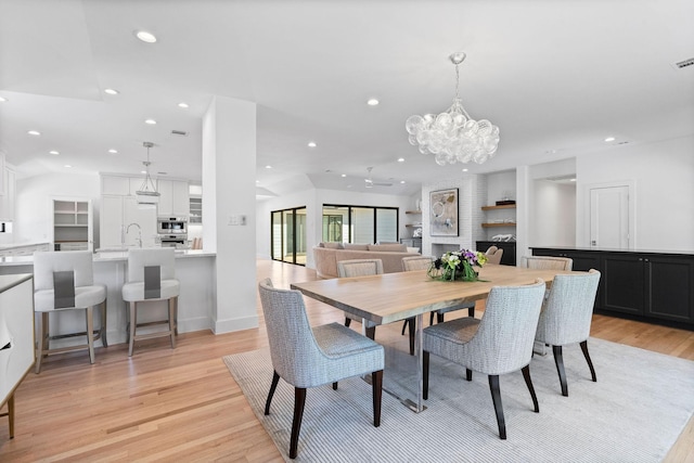 dining space featuring a notable chandelier, light hardwood / wood-style flooring, and sink