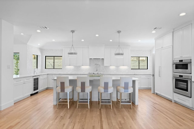 5658 Del Monte Dr, Houston, TX 77056 - kitchen with decorative backsplash, light wood-style flooring, light countertops, stainless steel double oven, and recessed lighting