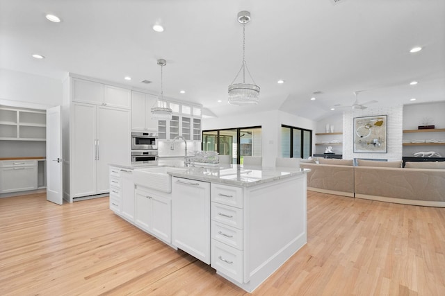 kitchen featuring white cabinets, hanging light fixtures, a kitchen island with sink, and ceiling fan with notable chandelier