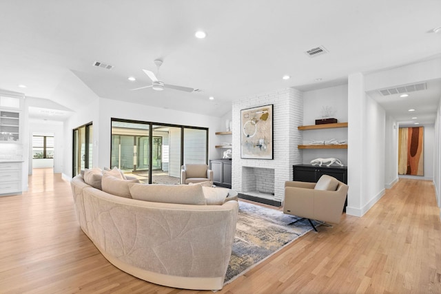 living room with lofted ceiling, a fireplace, ceiling fan, and light hardwood / wood-style flooring