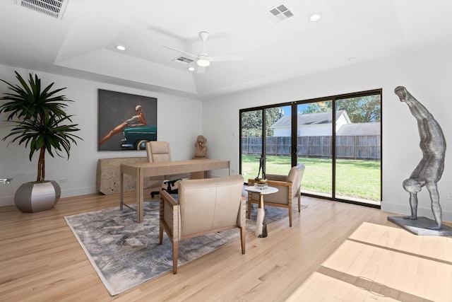 office with light wood-type flooring, ceiling fan, and a tray ceiling