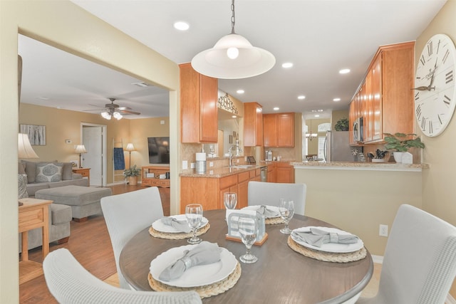 dining area featuring hardwood / wood-style flooring, ceiling fan, and sink