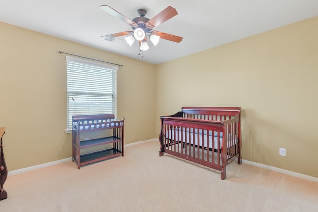 carpeted bedroom featuring a crib and ceiling fan