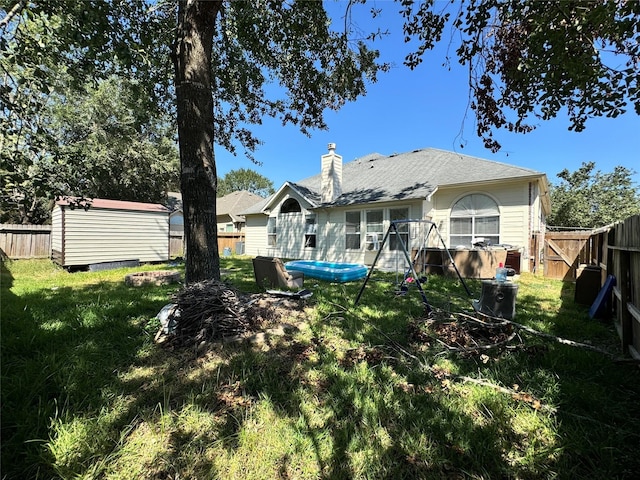 rear view of property with a yard and a storage shed