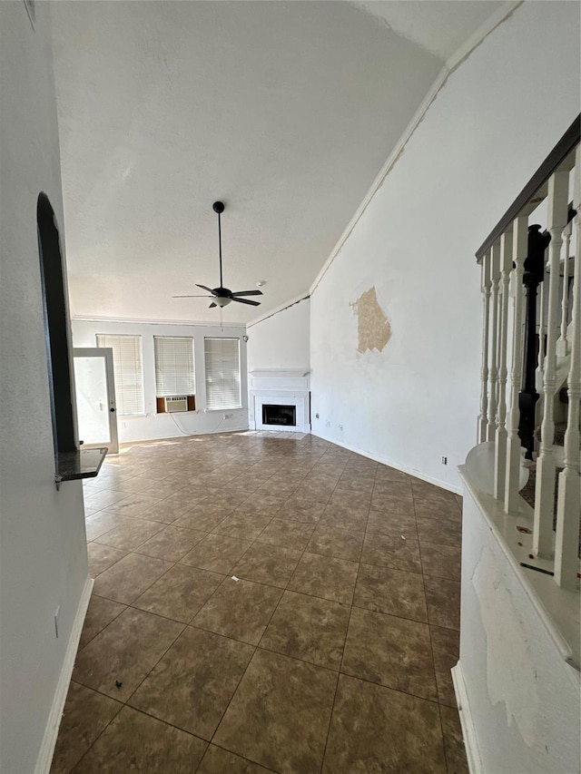 unfurnished living room featuring vaulted ceiling, dark tile patterned flooring, ornamental molding, and ceiling fan