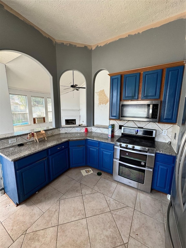 kitchen featuring stainless steel appliances, light tile patterned floors, blue cabinetry, and a textured ceiling