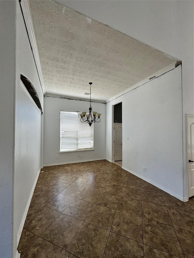 unfurnished dining area with dark tile patterned flooring, a textured ceiling, a chandelier, and crown molding