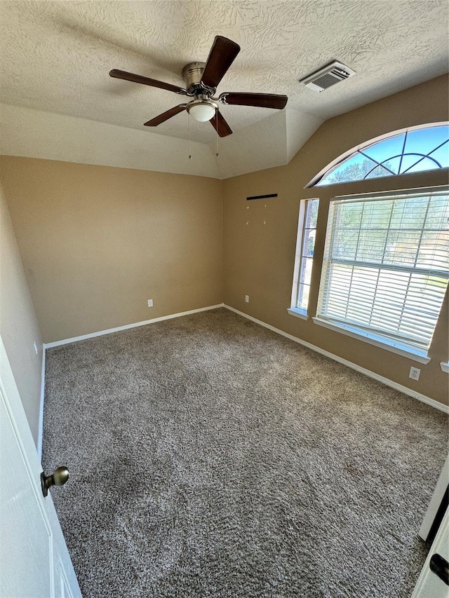 carpeted empty room with a textured ceiling, ceiling fan, and vaulted ceiling