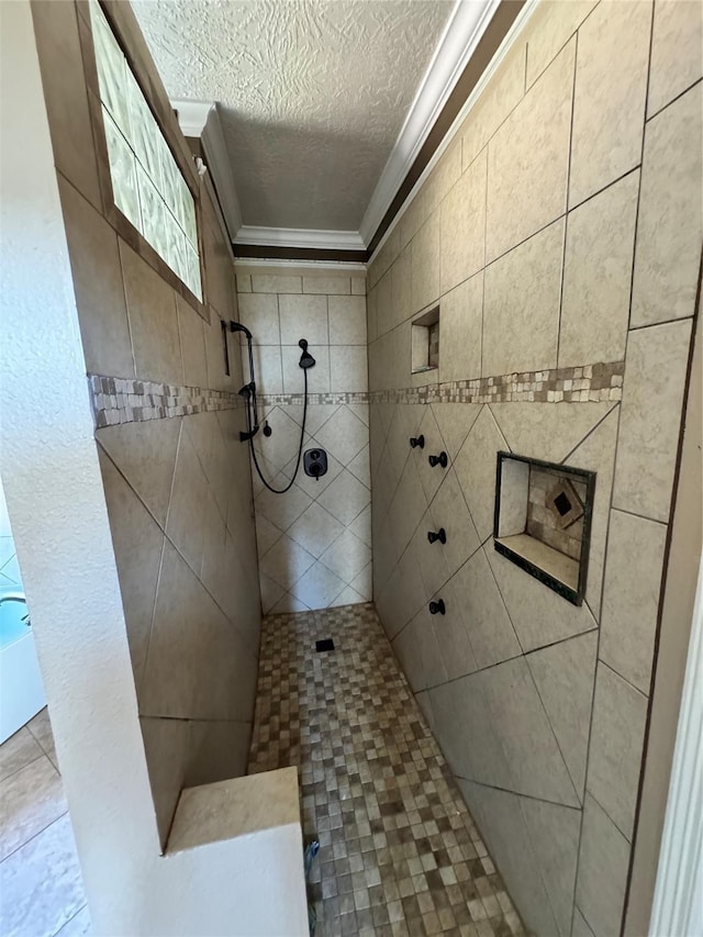 bathroom with a textured ceiling, ornamental molding, and tiled shower