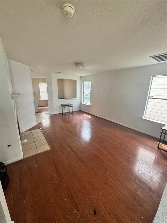 unfurnished living room with hardwood / wood-style flooring and a textured ceiling