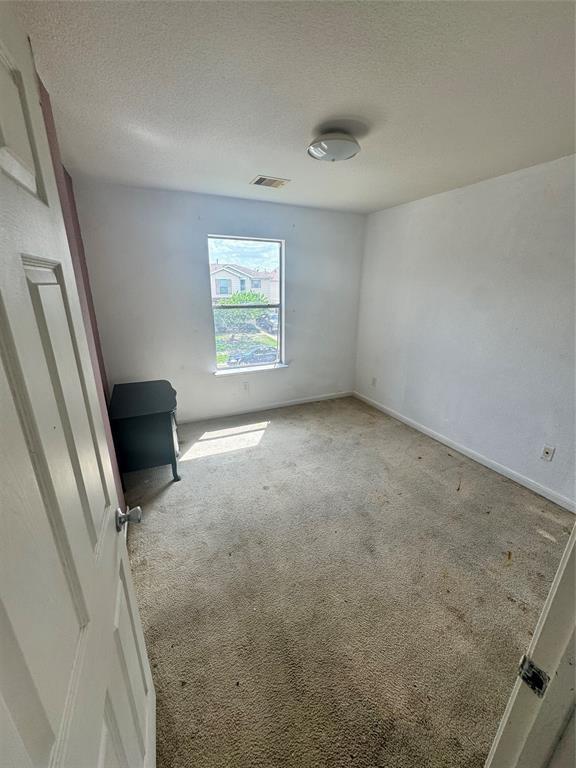 carpeted spare room featuring a textured ceiling