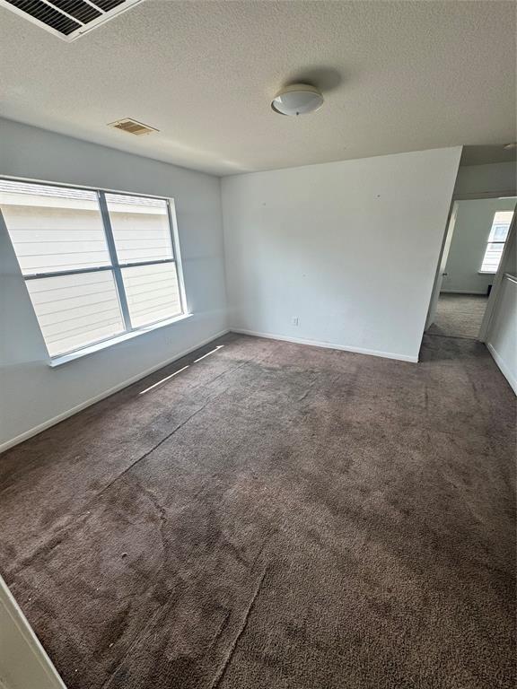 spare room with dark carpet and a textured ceiling