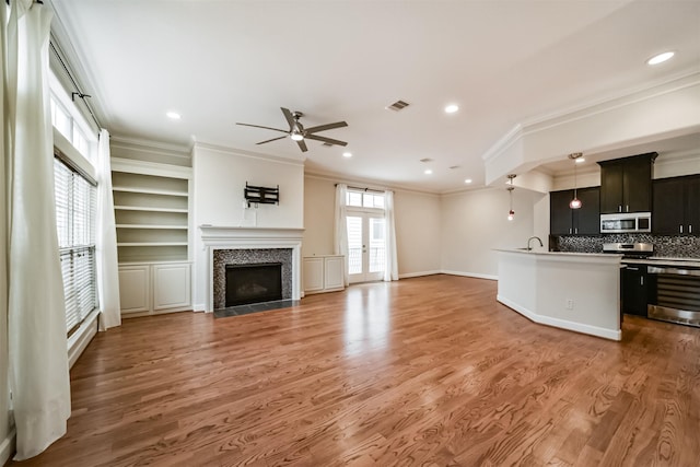 kitchen featuring hardwood / wood-style floors, an island with sink, decorative backsplash, a tiled fireplace, and ornamental molding