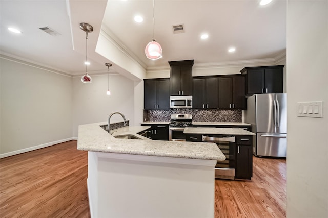 kitchen with a center island with sink, stainless steel appliances, light stone countertops, pendant lighting, and sink