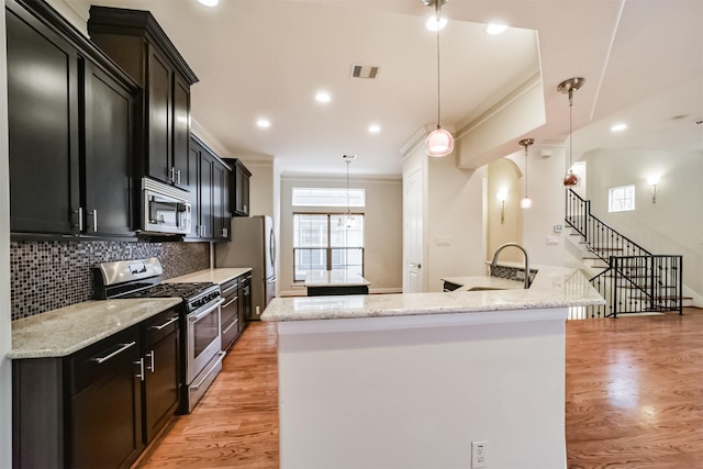 kitchen with light stone countertops, stainless steel appliances, tasteful backsplash, sink, and hanging light fixtures