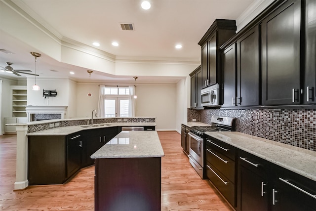 kitchen featuring ceiling fan, pendant lighting, a center island, sink, and appliances with stainless steel finishes