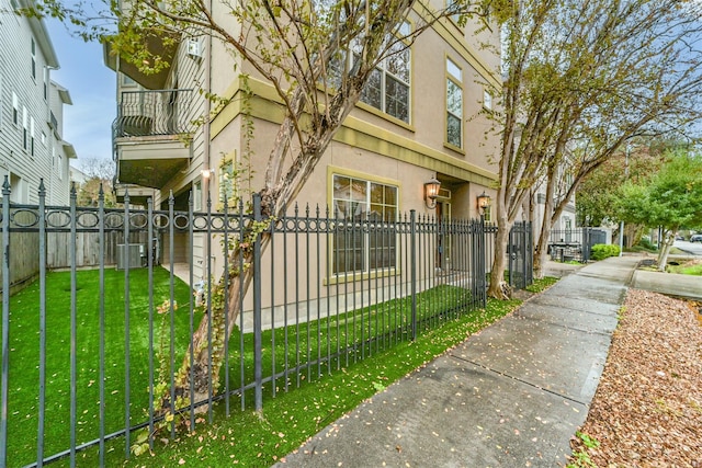 exterior space with a lawn, cooling unit, and a balcony