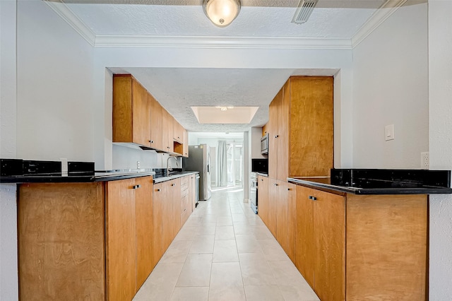 kitchen with a textured ceiling, ornamental molding, light tile patterned flooring, and appliances with stainless steel finishes