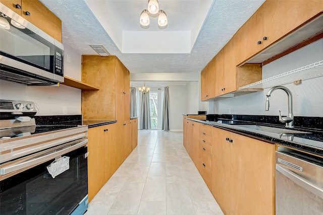 kitchen with a notable chandelier, dark stone countertops, sink, stainless steel appliances, and a textured ceiling