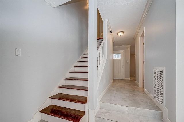 stairway featuring a textured ceiling and crown molding