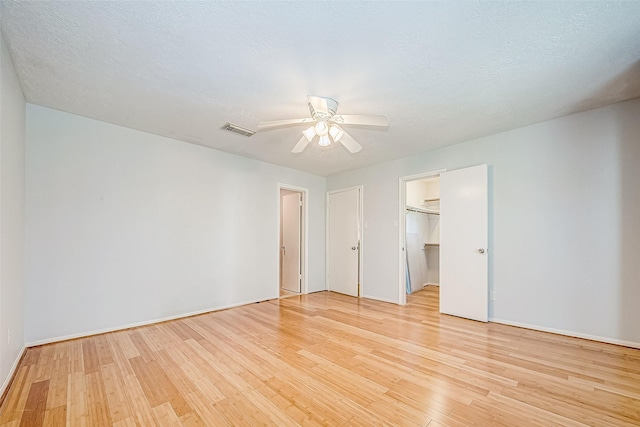 unfurnished room with light wood-type flooring, ceiling fan, and a textured ceiling