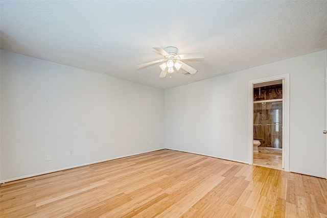 spare room with ceiling fan, light wood-type flooring, and a textured ceiling