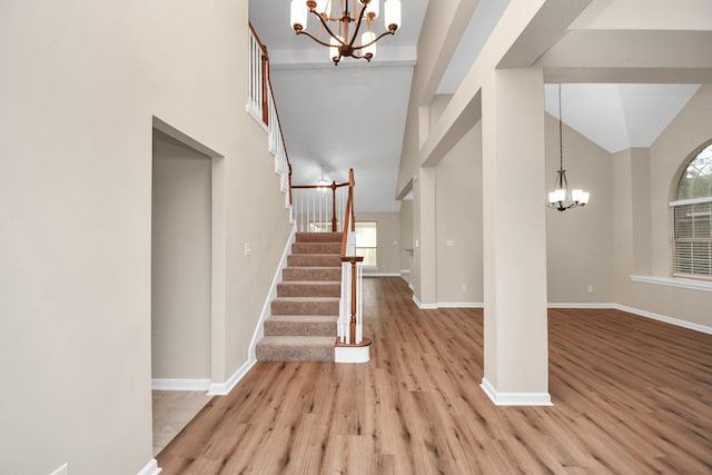 entrance foyer with a towering ceiling, an inviting chandelier, and light hardwood / wood-style flooring