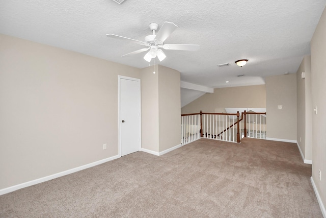 empty room with lofted ceiling, a textured ceiling, ceiling fan, and light colored carpet