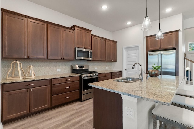 kitchen with sink, stainless steel appliances, decorative backsplash, and hanging light fixtures