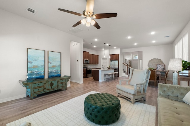 living room with ceiling fan, light hardwood / wood-style floors, and sink