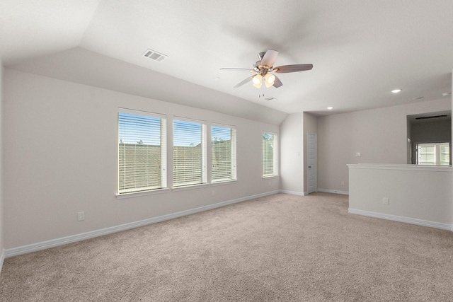 carpeted empty room with ceiling fan, lofted ceiling, and plenty of natural light