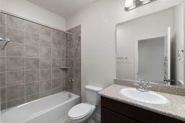 full bathroom featuring tiled shower / bath, vanity, and toilet