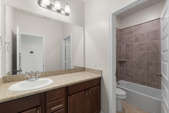 full bathroom featuring toilet, tile patterned flooring, vanity, and tiled shower / bath combo