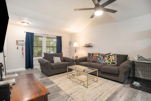 living room featuring ceiling fan, vaulted ceiling, and wood-type flooring