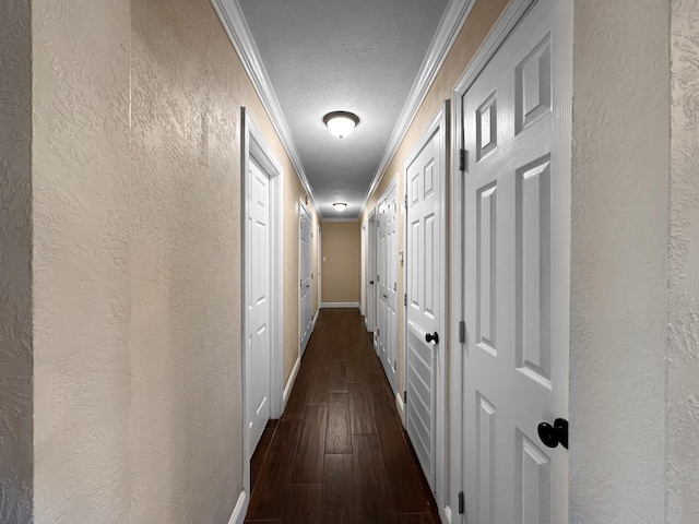 hall with a textured ceiling, dark wood-type flooring, and crown molding