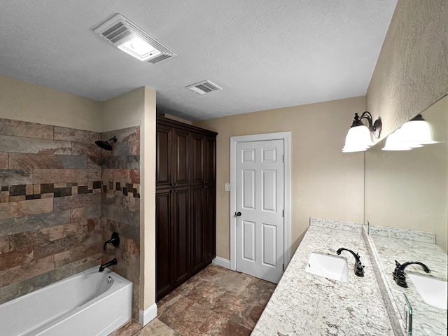 bathroom with vanity, a textured ceiling, and tiled shower / bath