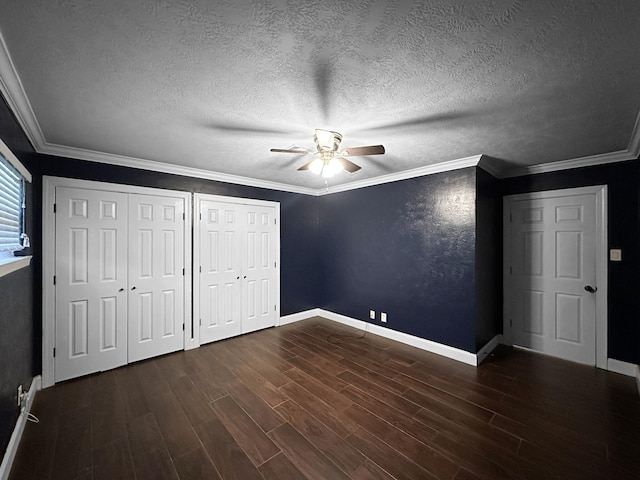 unfurnished bedroom featuring ceiling fan, multiple closets, ornamental molding, and a textured ceiling